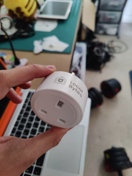 A hand holding a smart plug with the words Local Bytes written on it.